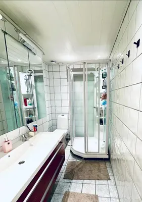 a white bathroom with a shower and a sink at 5 room apartment for Ski-World Championship in Trondheim