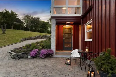 a red house with a table and chairs and purple flowers at 5 room apartment for Ski-World Championship in Trondheim