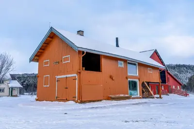 a large orange barn with snow on the ground at Leilighet i stall fra 1800-tallet in Os