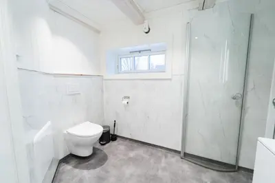 a white bathroom with a toilet and a shower at Leilighet i stall fra 1800-tallet in Os