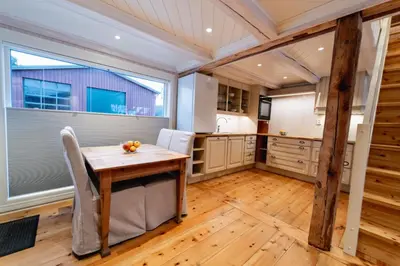 a kitchen with a wooden table and a large window at Leilighet i stall fra 1800-tallet in Os