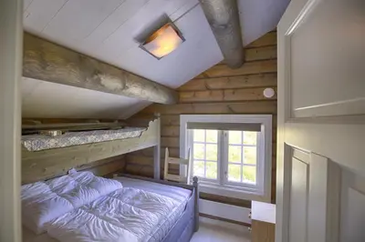 a bedroom with a bed and a window in a cabin at New Timber Lodge With Stunning Views And Comfort in Beitostøl