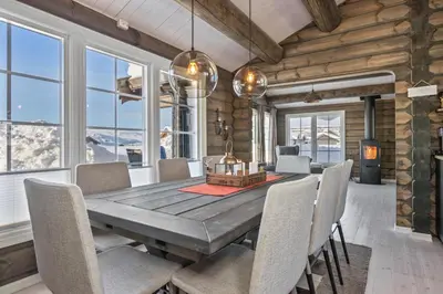 a dining room with a wooden table and chairs at New Timber Lodge With Stunning Views And Comfort in Beitostøl