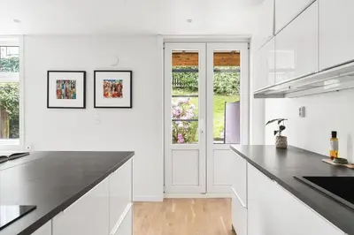 a kitchen with white cabinets and a black counter top at Urban retreat, traditional wooden house in Bergen in Bergen