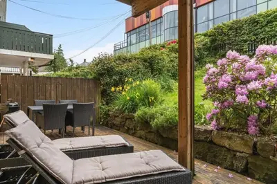 a patio with a table and chairs and flowers at Urban retreat, traditional wooden house in Bergen in Bergen