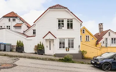a white house with a car parked in front of it at DINBNB Apartment l Skansen funhouse - 400m to Bryggen Gym & Parking in Bergen