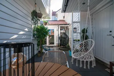 a porch with chairs and a table and a door at DINBNB Apartment l Skansen funhouse - 400m to Bryggen Gym & Parking in Bergen