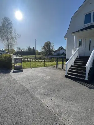 a white house with a porch and stairs to a yard at Sokkelleilighet i enebolig i Ålesund nær stranden in Ålesund