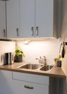 a kitchen with a sink and white cabinets at Unique apartment in midtown in Trondheim