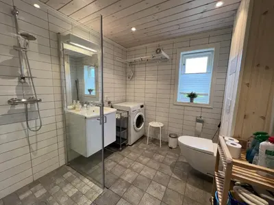 a bathroom with a shower and a sink and a washing machine at New Cozy Cabin By Ski Trails And Nature Paths in Beitostøl