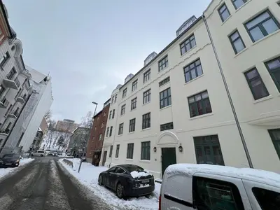 a black car parked next to a building in the snow at Apartment near City Center in Trondheim