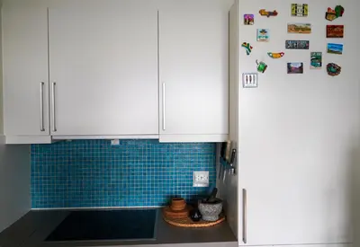 a kitchen with white cabinets and blue tile at Solrik leilighet på Byåsen in Trondheim