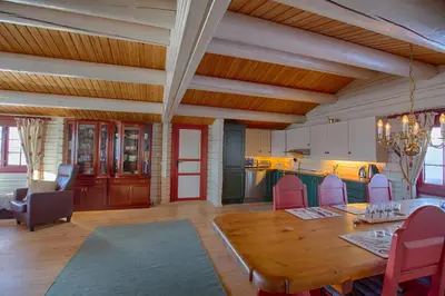 a living room with a wooden table and a kitchen at Charming Cabin Near Jotunheimen Trails in Beitostøl