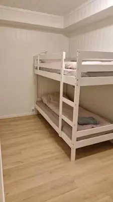 two white bunk beds in a room with a wooden floor at Lom in Lom