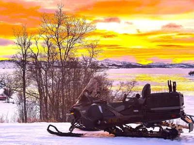 a motorcycle parked in the snow with a sunset at Møsstrond Turisthytte in Hovden