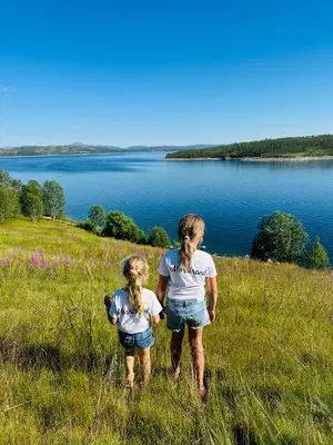 two girls walking in the grass near a lake at Møsstrond Turisthytte in Hovden