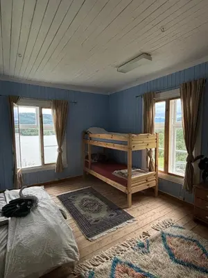 a bedroom with a bunk bed and two windows at The blue room at Vevstogo - cosy with a mesmerizing view, sauna and eco living in an old school house in Løken