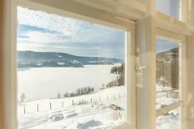 a window with a view of a snow covered field at The blue room at Vevstogo - cosy with a mesmerizing view, sauna and eco living in an old school house in Løken
