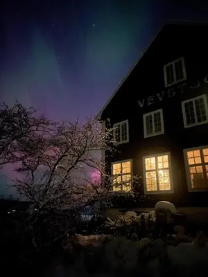 a house lit up at night with the lights on at The blue room at Vevstogo - cosy with a mesmerizing view, sauna and eco living in an old school house in Løken