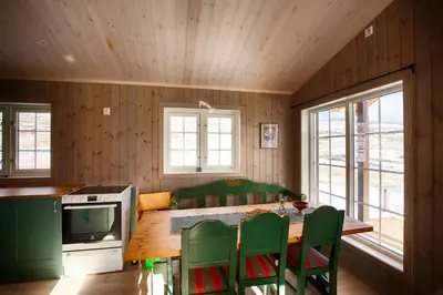 a kitchen with a wooden table and green chairs at Modern Cabin At The Foot Of Bitihorn in Beitostøl