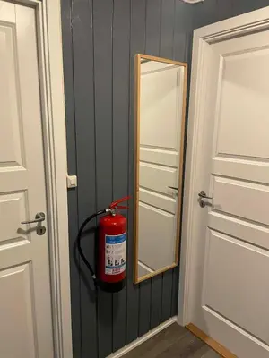 a fire extinguisher hanging on a wall next to a mirror at Leilighet i Sør-Fron kommune in Sør-Fron