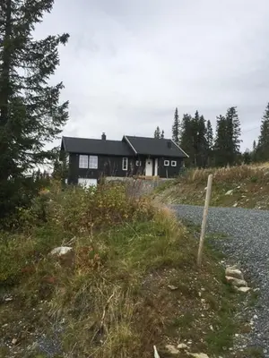 a house sitting on top of a hill next to a road at Mountain Cabin With Views At Skeikampen in Svingvoll