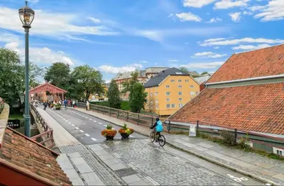 a person riding a bike on a street with buildings at Central apartment in idyllic Bakklandet in Trondheim