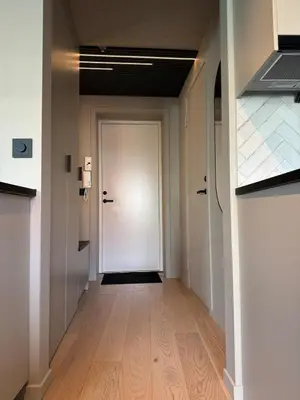 an empty hallway with a white door and wooden floors at Central apartment in idyllic Bakklandet in Trondheim