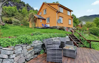 a house with a stone wall and chairs on a wooden deck at 3 Bedroom Lovely Home In Valen in Valen
