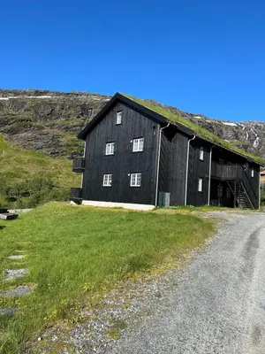 a black barn with a grass roof on a road at Leilighet i 1 etg Røldal in Håra