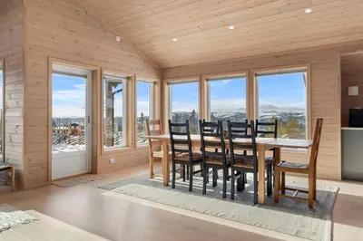 a dining room with a table and chairs and windows at Modern Family Cabin at Norefjell - Views and Hiking in Eggedal