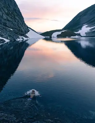 a person swimming in a body of water at The Crux Nordic Design Mountain Cabin in Åndalsnes