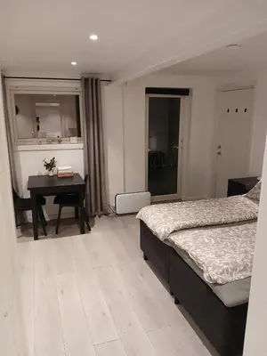 a bedroom with two beds and a table and a desk at studio apartment 24 sqm in Trondheim