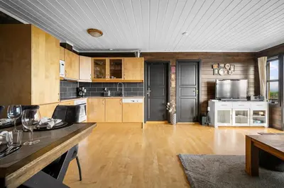 a large kitchen with wooden cabinets and a dining table at Lovely apartment with amazing view and sauna in Skulestadmo