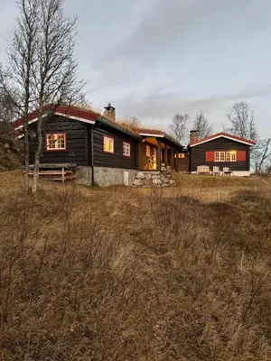 a large wooden house in the middle of a field at Sjarmerende hytte på Geilo med 5 soverom in Geilo