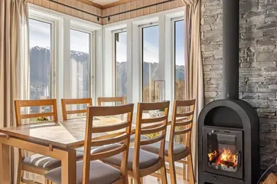 a dining room with a table and a fireplace at Peaceful Cabin With Spa On Osterøy in Bruvik