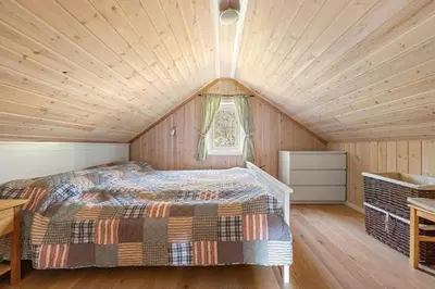 a bed in a room with a wooden ceiling at Peaceful Cabin With Spa On Osterøy in Bruvik
