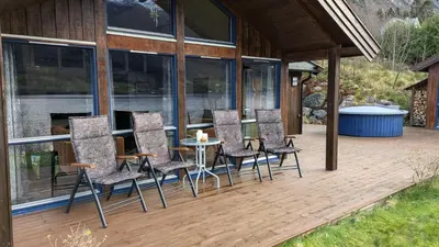 a deck with chairs and a table on a house at Flott hytte i Vistdal, Romsdal in Myklebostad