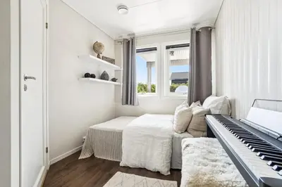 a white bedroom with a bed and a piano at Moderne rekkehus nært Ålesund in Valderøya