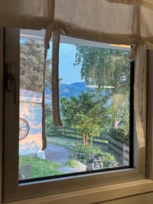 a window with a view of a garden through it at Family Cabin With Panoramic Views Of Tyrifjorden in Nes