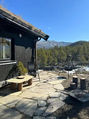 a picnic table and a tripod next to a building at Charming Cabin In Jotunheimen in Vaga