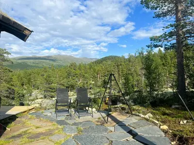 two chairs sitting on a stone patio with mountains in the background at Charming Cabin In Jotunheimen in Vaga