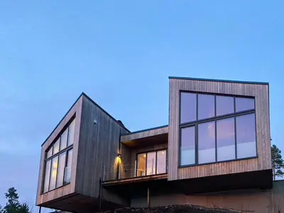 a house with glass windows on the side of it at Architect-Designed Cabin With View In Molde in Røvik