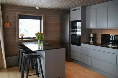 a kitchen with white cabinets and a counter with stools at Mountain Cabin By The Ski Trails In Rauland in Rauland