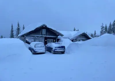 two cars parked in front of a house covered in snow at Family Cabin With Ski In Ski Out in Trysil