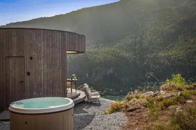 a hot tub sitting next to a bench next to a mountain at The Sognefjord Cabin in Kaupanger