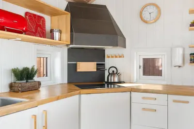 a kitchen with white cabinets and a clock on the wall at Panoramautsikt i Valdres Perfekt for ski og fjellturer året rundt in Aurdal