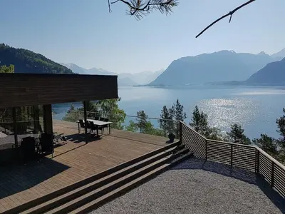 a wooden deck with a table and a view of a lake at Fjord Cabin With Panoramic Views In Rauma in Innfjorden