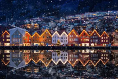 a city lit up at night with its reflection in the water at Apt 500 m to Bryggen - Perfect location in Bergen