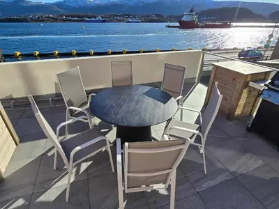 a table and chairs on the deck of a boat at Oceanview Apartment Aalesund in Ålesund